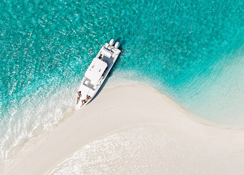 A boat nosing onto a sandbar between islands in The Bahamas