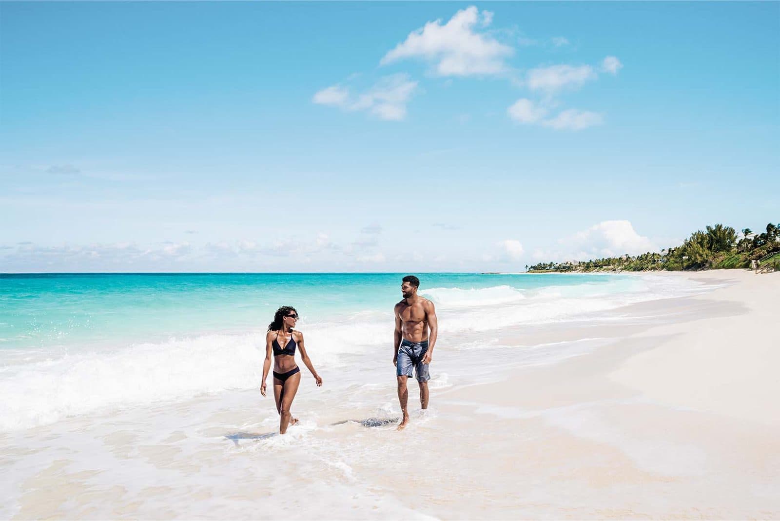 A couple walking along a white-sand beach near Nassau